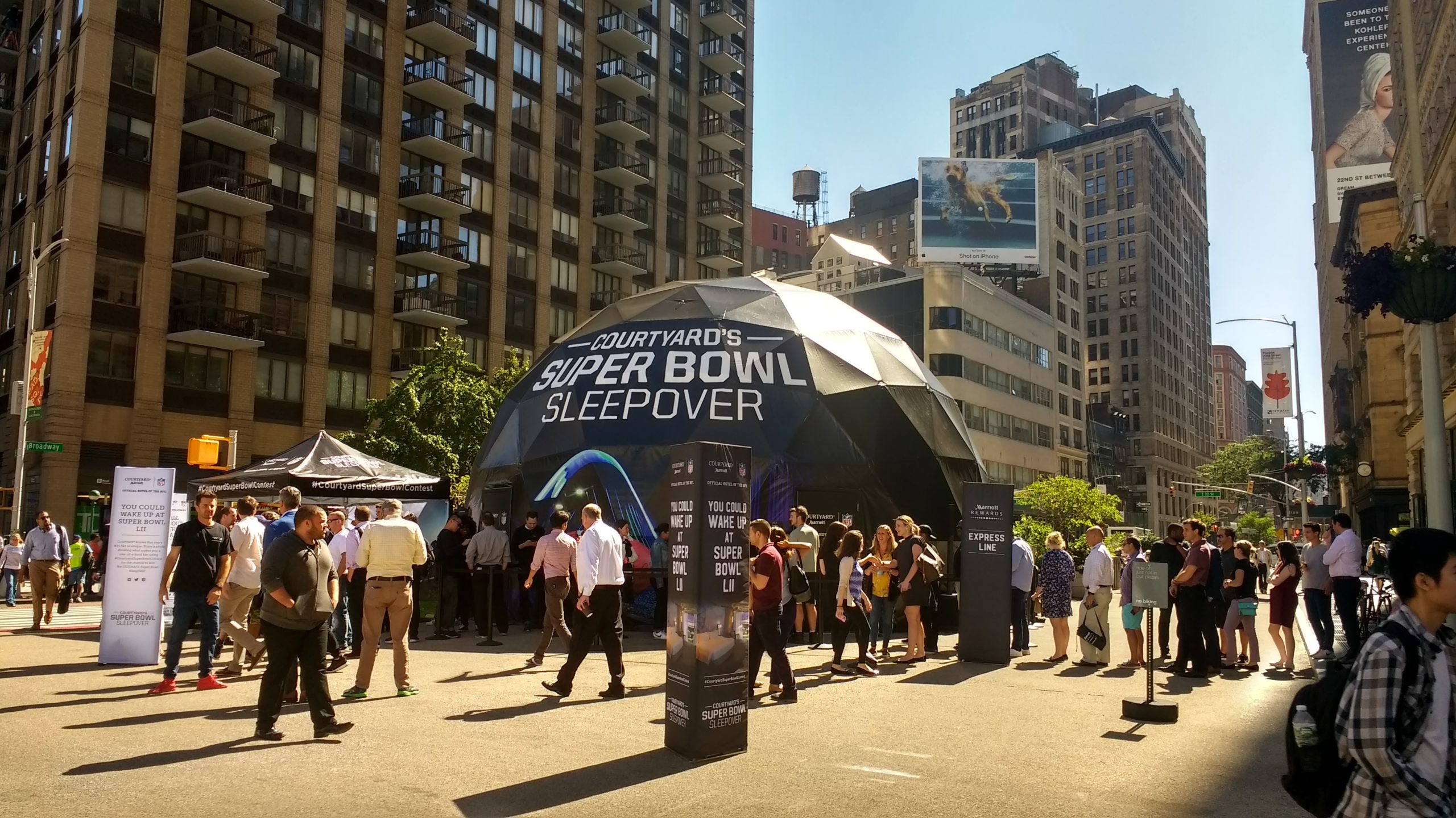 A Courtyard Marriot branded dome is surrounded by a crowd of people for an NFL super bowl activation